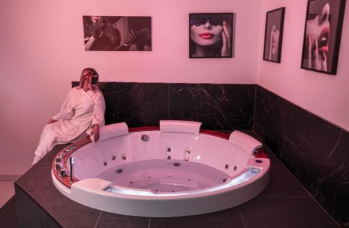 a woman sitting in front of a tub in a bathroom at L'OLYMPE DES SENS in Portiragnes