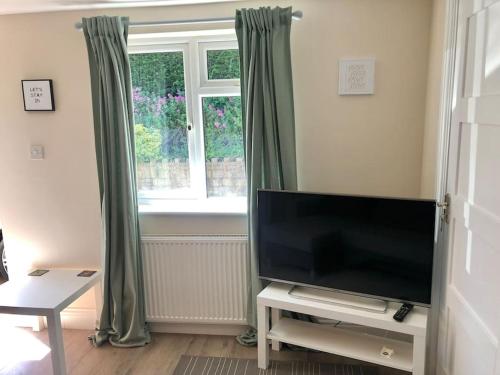 a living room with a flat screen tv and a window at Quiet and cosy flat, close to Bath Centre in Bath