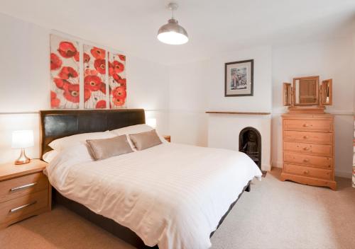 a bedroom with a large bed and a fireplace at Poppy Cottage in Briston