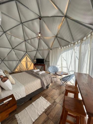 a room with a bed and a table in a tent at Glamping Salta in Cabra Corral