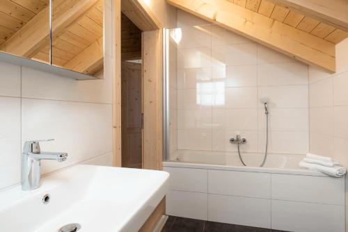 a bathroom with a shower and a sink and a tub at Feriendorf Koralpe Wellness Edelweiß in Frantschach