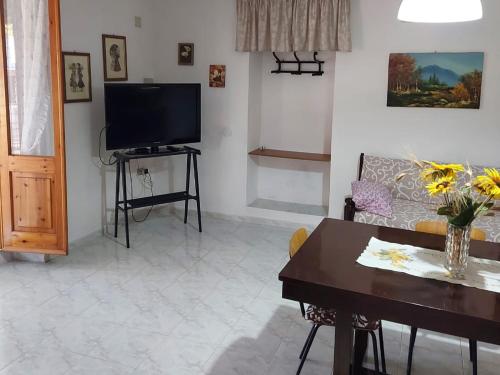 ein Wohnzimmer mit einem TV und einem Tisch in der Unterkunft A cà du Sepino a due passi dal mare in Carloforte