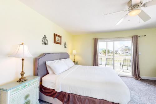 a bedroom with a bed with a ceiling fan and a window at Shore To C in St. George Island