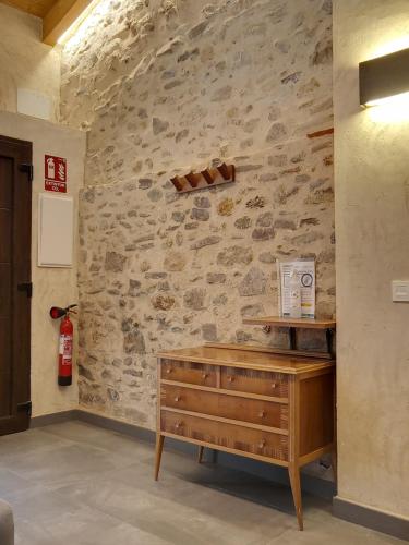 a room with a stone wall with a wooden dresser at Casa rural El Forn d'Alcudia de Veo in Alcudia de Veo