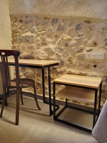 two tables and a chair next to a stone wall at Casa rural El Forn d'Alcudia de Veo in Alcudia de Veo