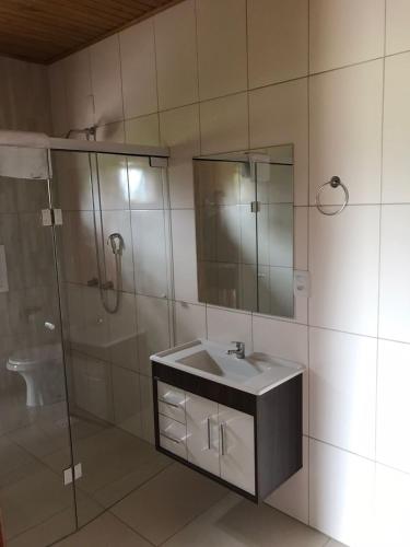 a bathroom with a sink and a glass shower at Pousada Caminhos da Serra in Bom Retiro