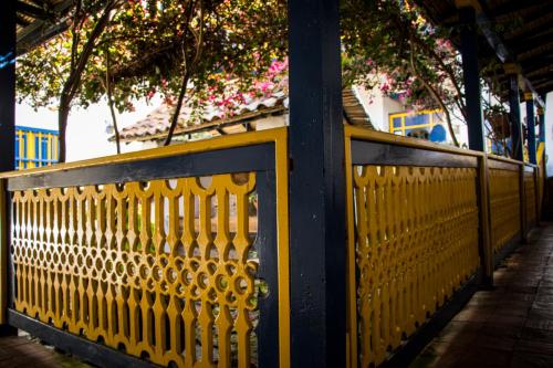 a yellow fence in front of a building with flowers at Hotel Museo la Posada del Molino in El Cocuy