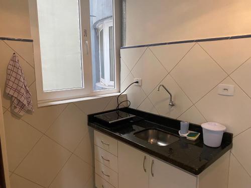 uma pequena cozinha com um lavatório e uma janela em POSIT APARTAMENTOS em Curitiba