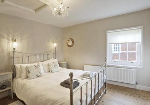 a bedroom with a bed and a window and a chandelier at Jasmine Cottage in Woodbridge