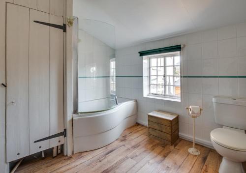 ein Bad mit einer Badewanne und einem WC in der Unterkunft Jasmine Cottage in Woodbridge