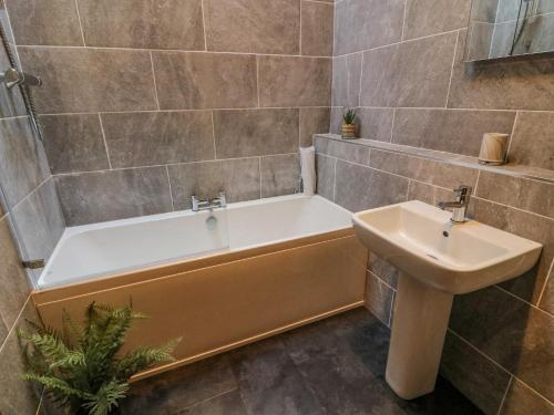 een badkamer met een bad en een wastafel bij No 2 The Mews in Carnforth