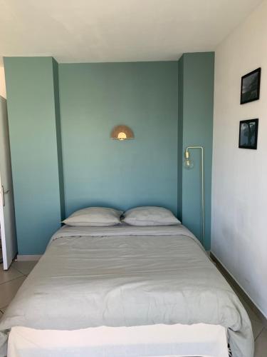 une chambre avec un lit avec un mur bleu dans l'établissement Joli Studio proche quartier Timone Climatisé, à Marseille