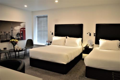 Bella Vista Hotel & Self Catering Suites في كوب: غرفة نوم بسريرين وطاولة وكراسي