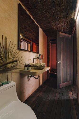 a bathroom with a toilet and a wooden floor at Radhoo Tulum in Tulum