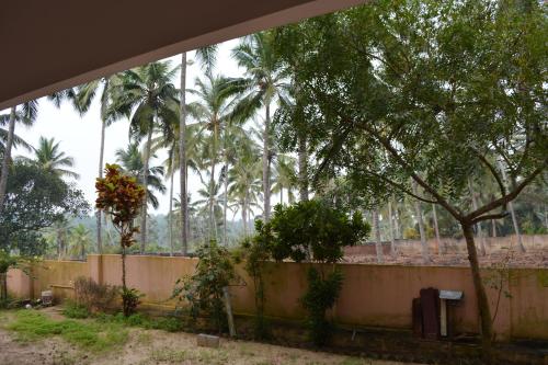 a group of palm trees behind a fence at Indeevaram Apartments in Kovalam