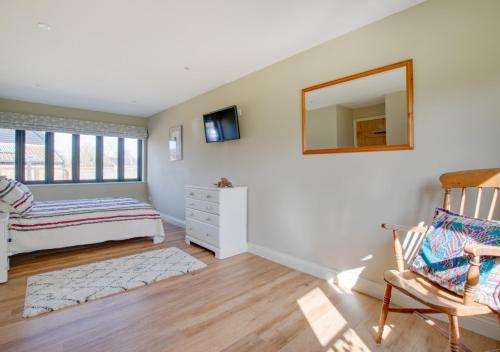 een slaapkamer met een bed, een spiegel en een stoel bij The Cart Lodge in Needham