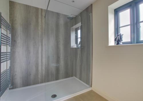 baño con ducha y puerta de cristal en The Cart Lodge, en Needham