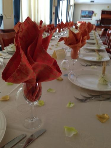 a long table with red flowers in a wine glass at Hotel Niagara in Catanzaro Lido