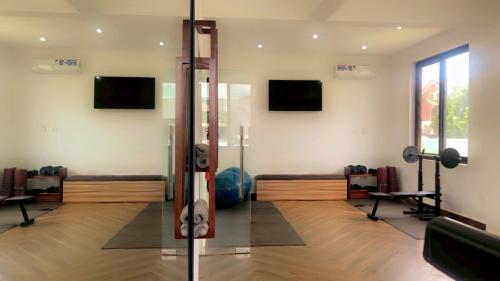 a room with a gym with benches and monitors at Cozy Apartments at East Airport in Burma Camp