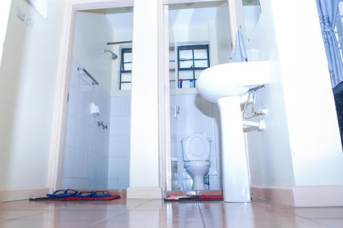 La salle de bains blanche est pourvue de toilettes et d'un lavabo. dans l'établissement Baraka Homes, à Kisumu
