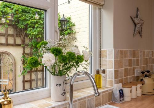 a kitchen sink with a vase of flowers in a window at The Hideout in Beccles
