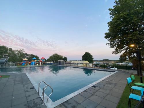 a large swimming pool with chairs and a playground at LUXUS Cube Ferienhaus Chalet am See mit Schwimmbad in Lathum NL in Lathum