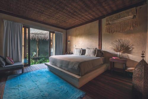 a bedroom with a large bed and a balcony at Radhoo Tulum in Tulum