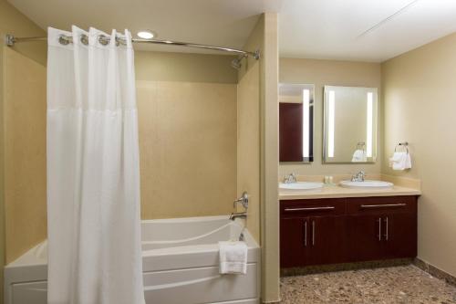 a bathroom with a white shower curtain and two sinks at Staybridge Suites Las Vegas - Stadium District in Las Vegas
