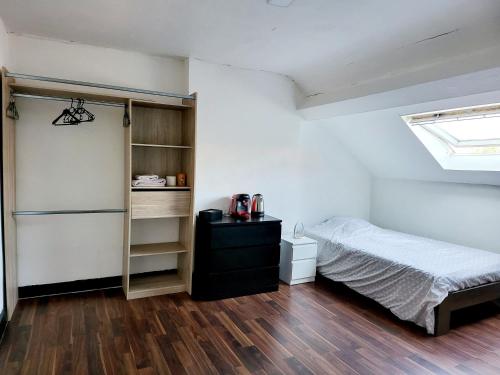 een slaapkamer met een bed en een boekenplank bij Chambre privée au 3e étage sans ascenceur en plein centre de Charleroi in Charleroi