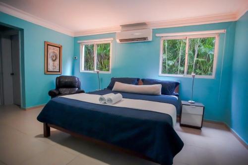 a blue bedroom with a bed and a chair at Impresionante villa con piscina Metro Country Club in Paraíso