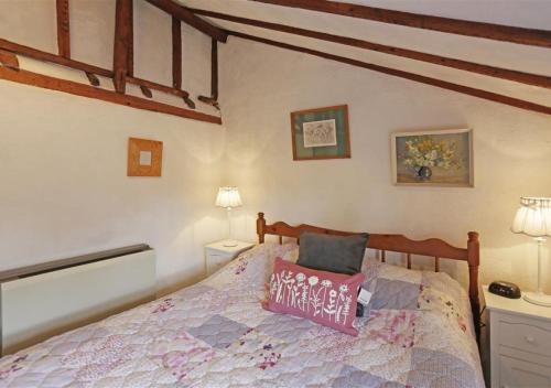 a bedroom with a bed with a pink pillow on it at Rose Cottage in Bealings