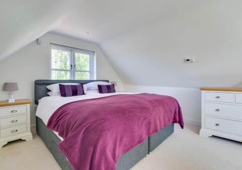 um quarto com uma cama grande e um cobertor roxo em Mallards em Whepstead