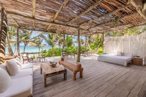 um pavilhão com uma cama e um sofá num deque em La Valise Tulum em Tulum