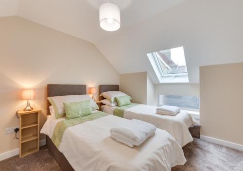 two beds in a attic bedroom with a window at Ardley Cottage Badger in Waldingfield