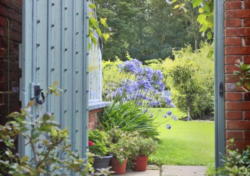an open door to a garden with flowers and plants at Garden View in Parham