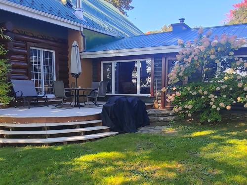 a house with a patio with a table and chairs at Le petit Montebello in Grenville-sur-la-Rouge
