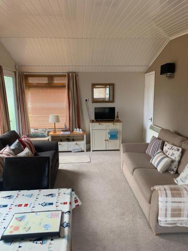 una sala de estar con un sofá y una mesa en Dartmouth 2 Bed Detached Chalet 144 Norton Park, en Dartmouth