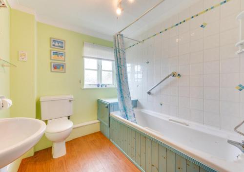 a bathroom with a toilet and a tub and a sink at 1 Chequers Row in Friston
