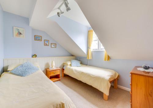 a attic bedroom with two beds and a window at 1 Chequers Row in Friston