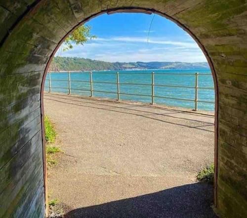 an arch in a brick wall with a view of the water at Adorable bedsit for you, partner and your pet! in Pembrokeshire