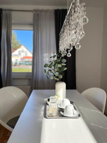 a dining room table with a chandelier and white chairs at DEICHHÜTTE NORDDEICH in Norddeich