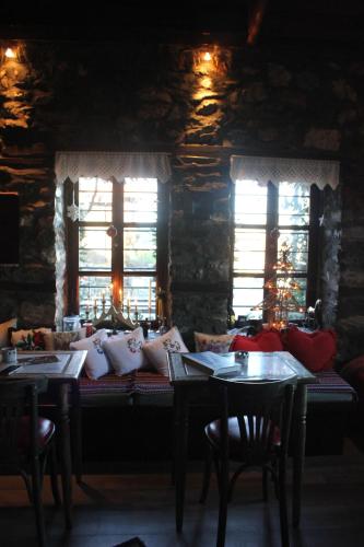 a dining room with two tables and two windows at Feggaropetra Inn Magic Mountain House in Palaios Panteleimon