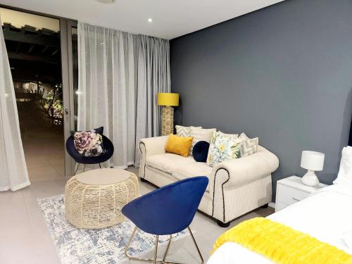 a living room with a white couch and a blue wall at Sugar Shores - Studio Apartment in Sibaya