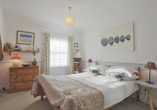 a bedroom with a large white bed and a window at Pebbles Cottage in Southwold