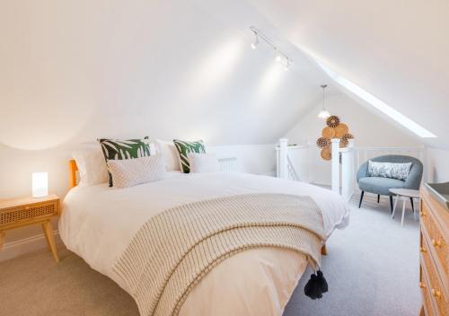 a white bedroom with a bed and a chair at Lux Lodge in Playford