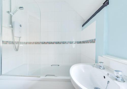 a white bathroom with a sink and a shower at Corner Cottage in Wangford