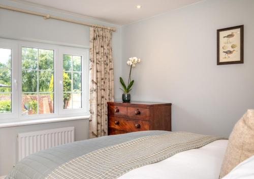 a bedroom with a bed and a dresser and a window at Riverside Lodge in Beccles
