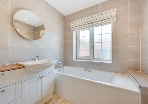 a bathroom with a sink and a tub and a mirror at Riverside Lodge in Beccles