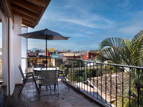 einen Balkon mit einem Tisch, Stühlen und einem Sonnenschirm in der Unterkunft Hotel Casa Real Del Café in Coatepec