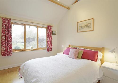 a bedroom with a white bed and a window at Meadow Cabin in Henstead